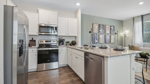 Kitchen peninsula with white cabinets, granite countertops and stainless steel appliances.
