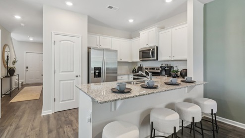 Kitchen peninsula with white cabinets, granite countertops and stainless steel appliances.