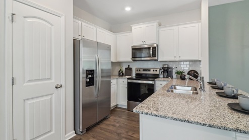 Kitchen peninsula with white cabinets, granite countertops and stainless steel appliances.