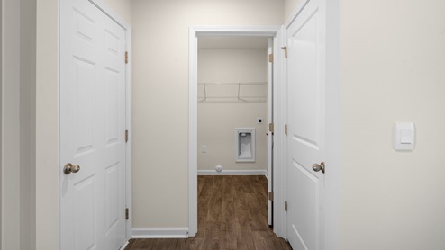 hallway leading to laundry room with white doors