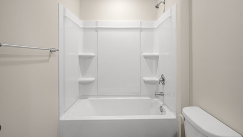 bathroom with double sinks and bathtub and toilet