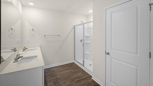 primary bathroom with double sinks and a toilet and walk in shower