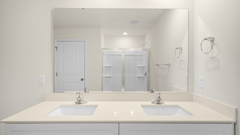 primary bathroom with double sinks and a toilet and walk in shower