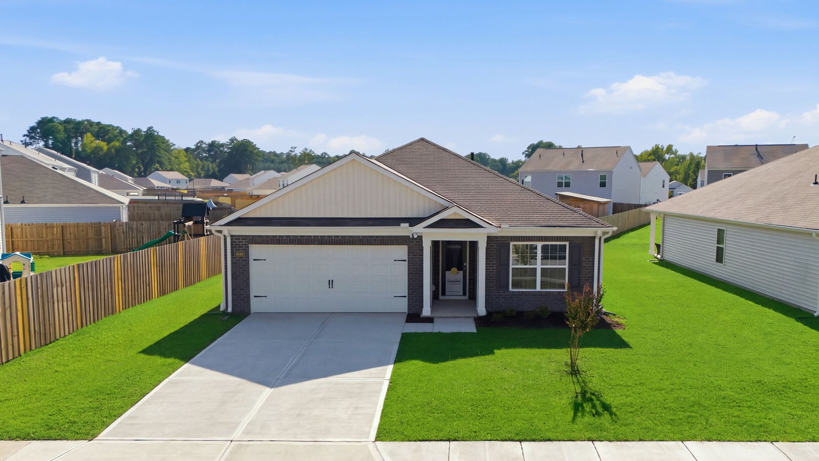 front view of brick one story home with yard and two car garage