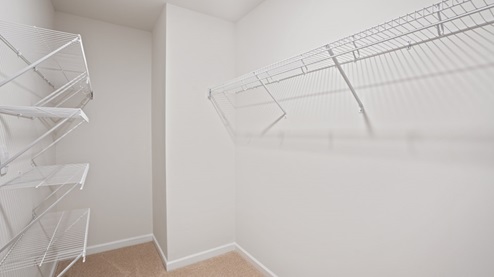 large walk in closet with built in wire shelving and carpet flooring