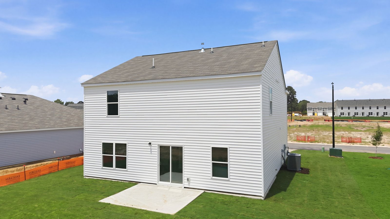 rear view of two story home and back patio pad