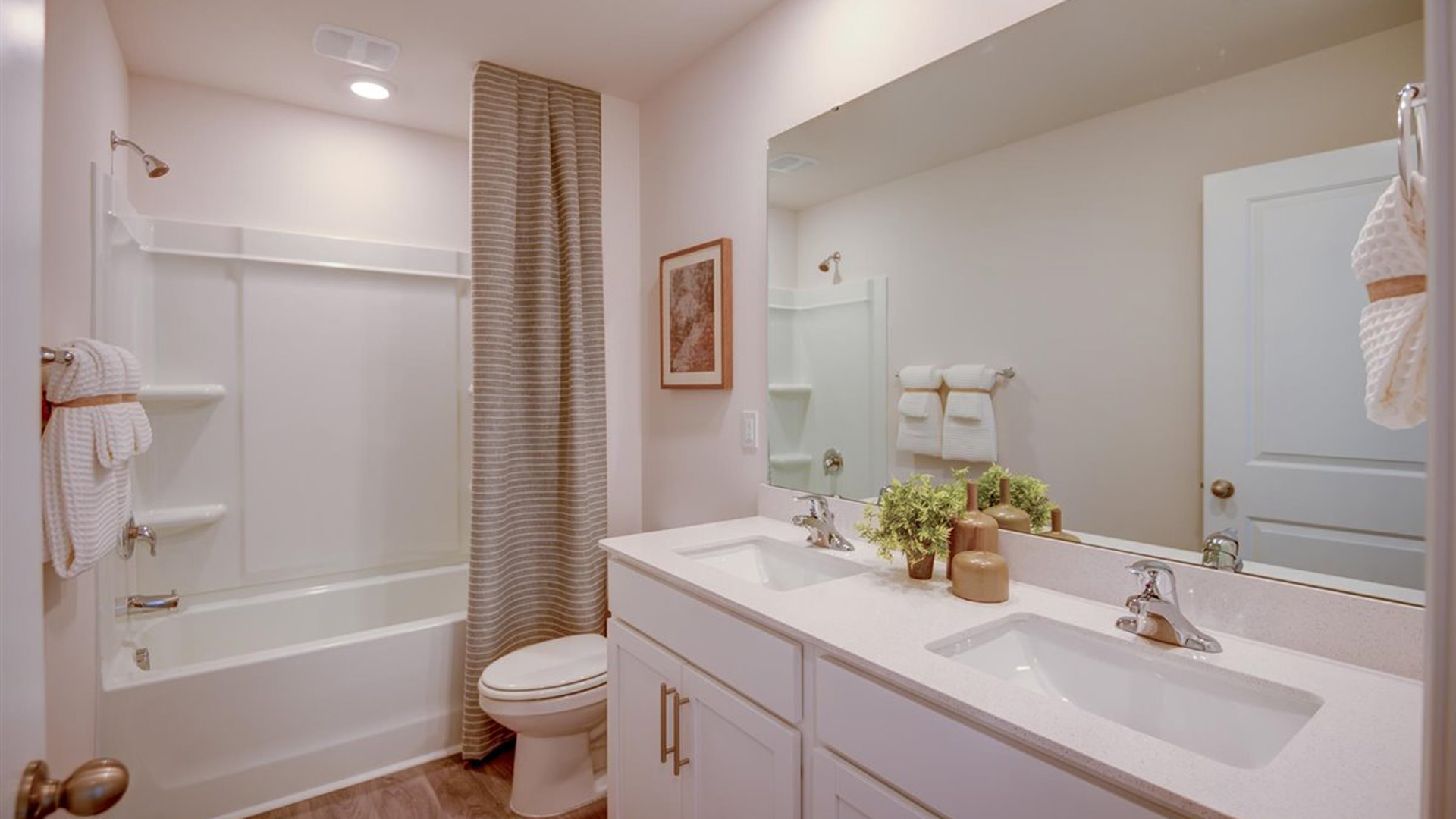 Bright bathroom with tub and large vanity and mirror.