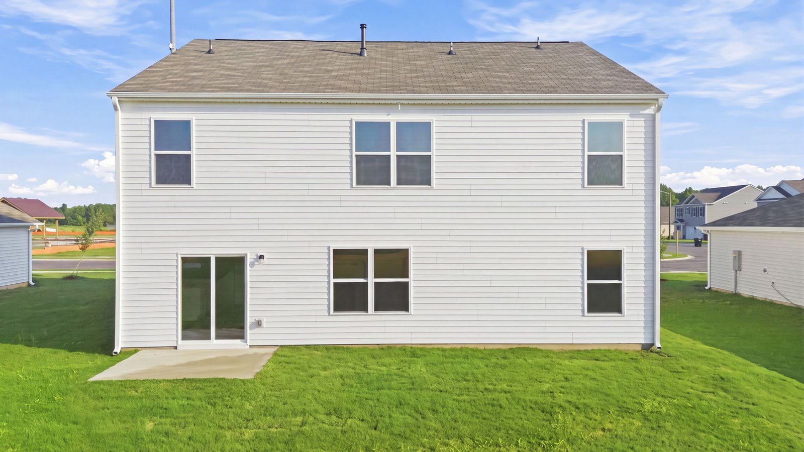 rear view of two story home and patio pad
