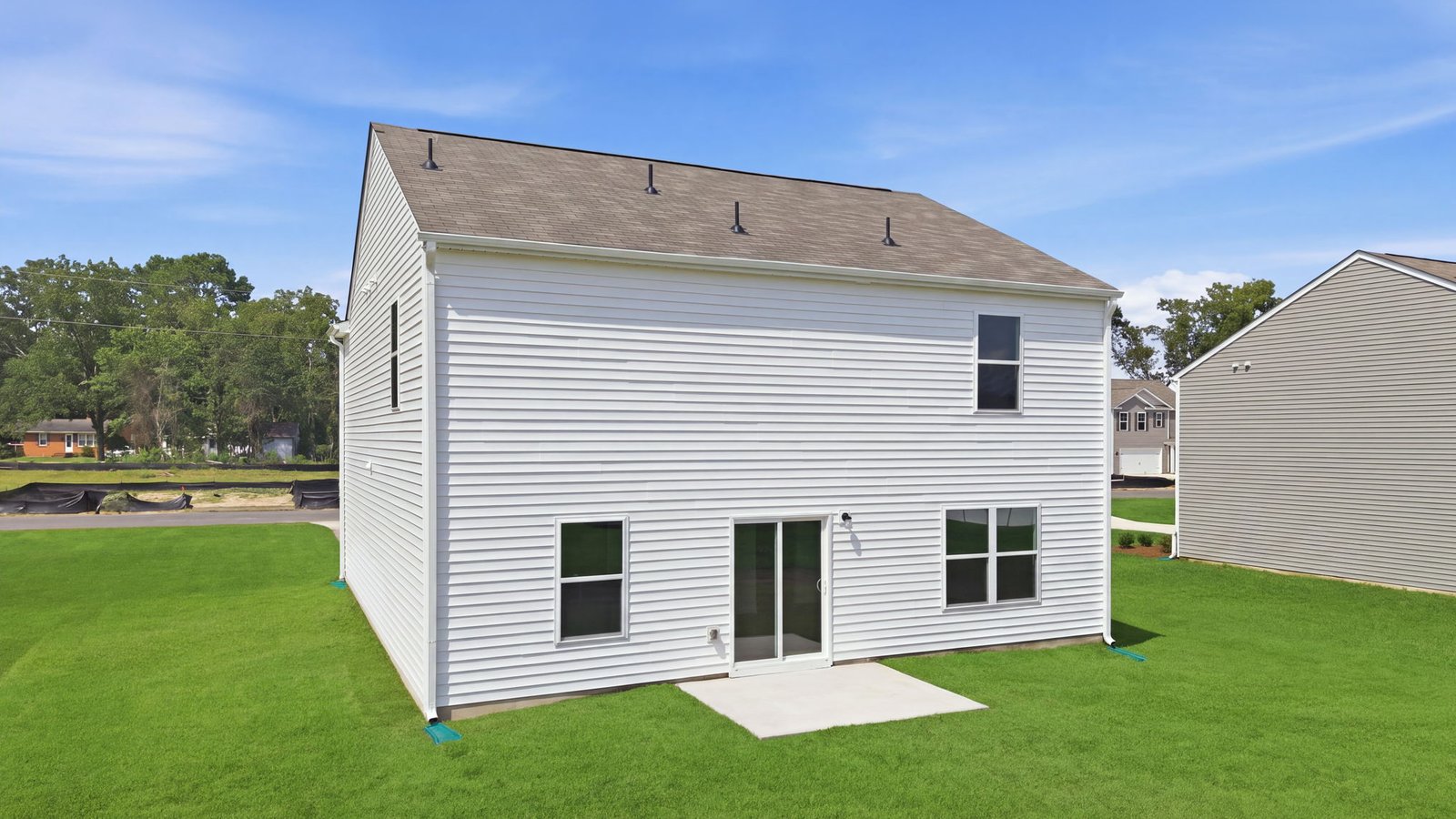 rear view of the rear of the home and yard with back patio pad