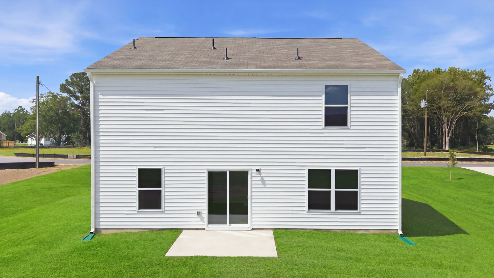 rear view of the rear of the home and yard with back patio pad