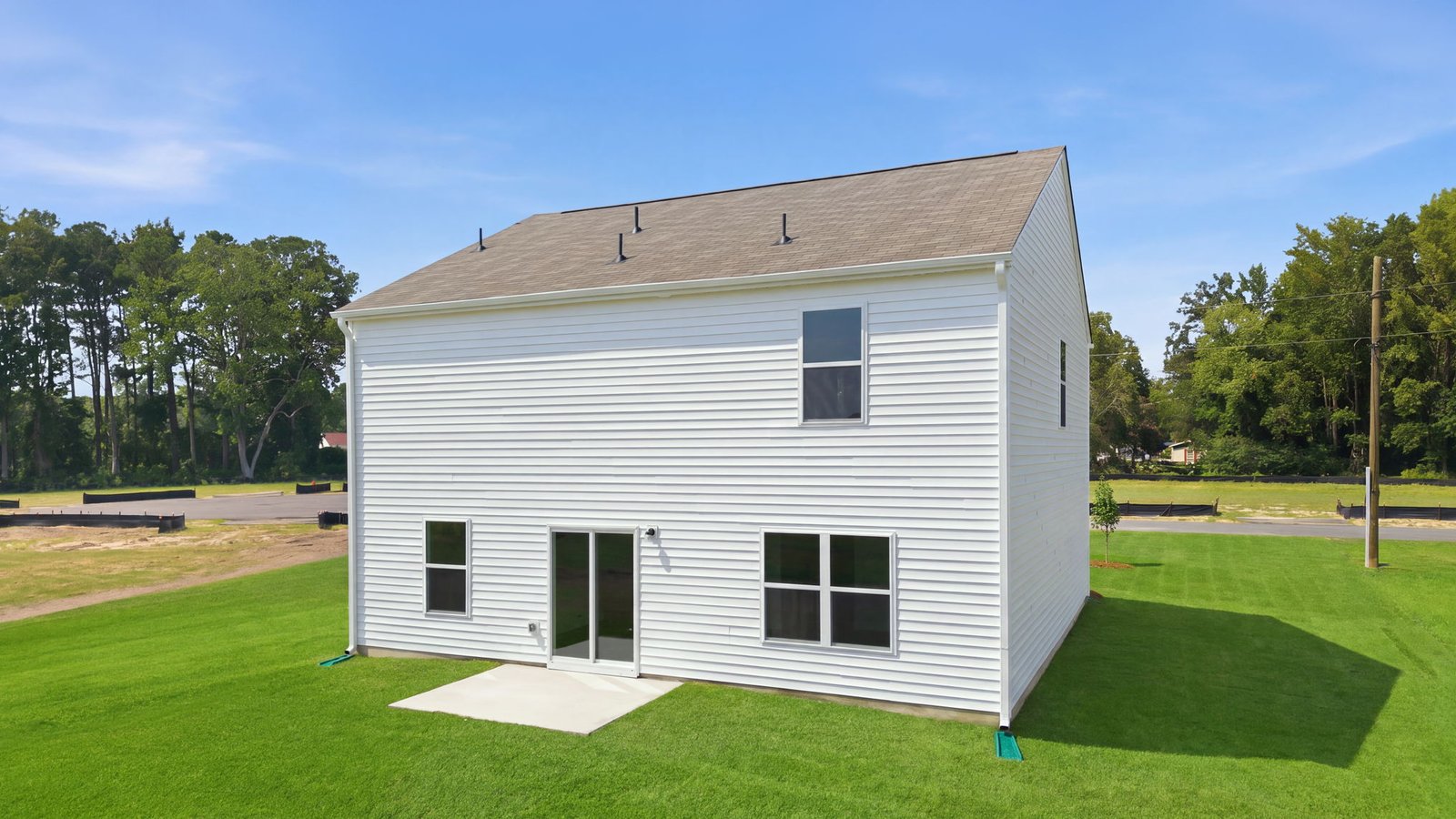 rear view of the rear of the home and yard with back patio pad