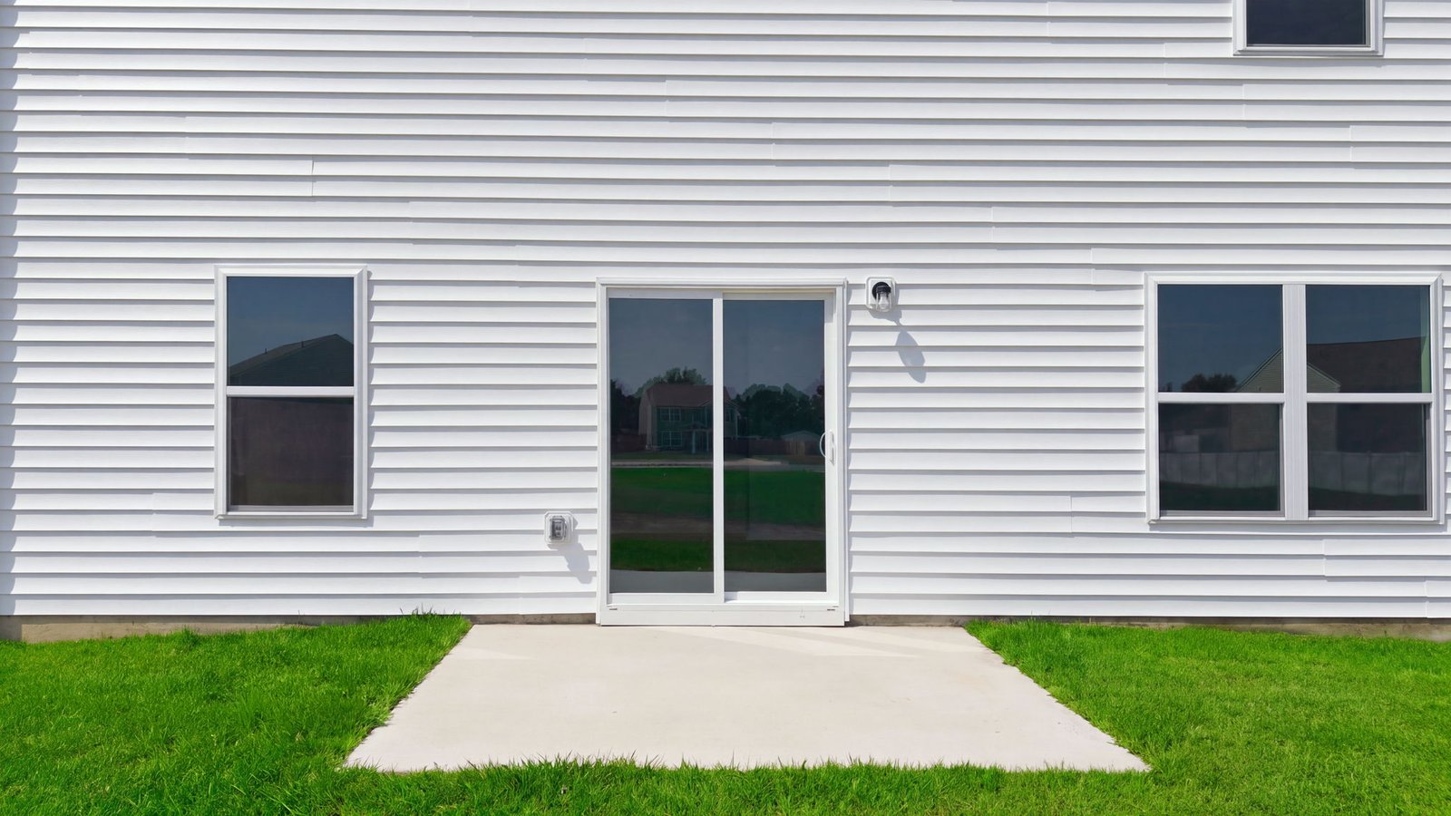 rear view of the rear of the home and yard with back patio pad