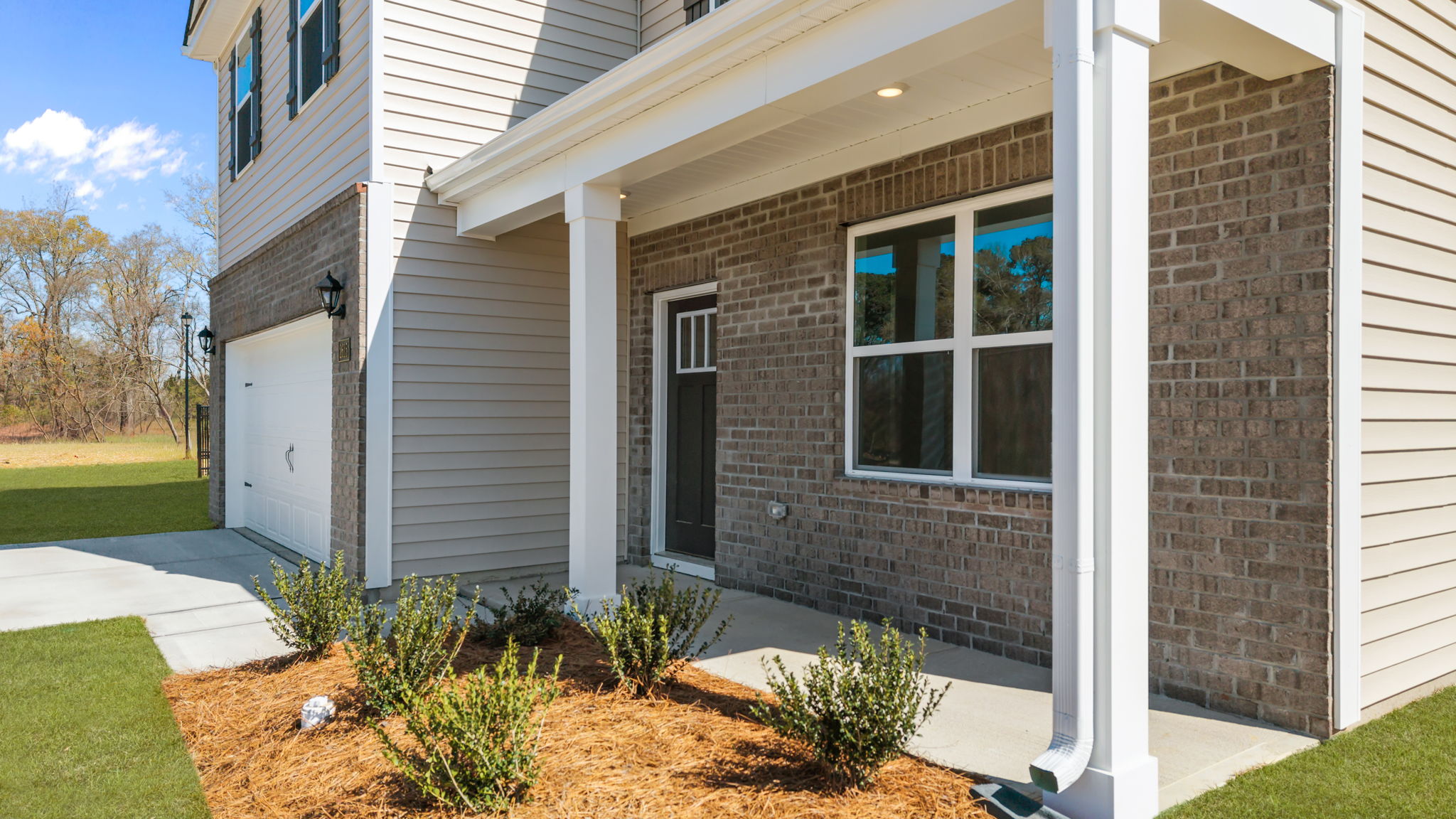 Beautiful covered front porch with beams and beautiful landscaping
