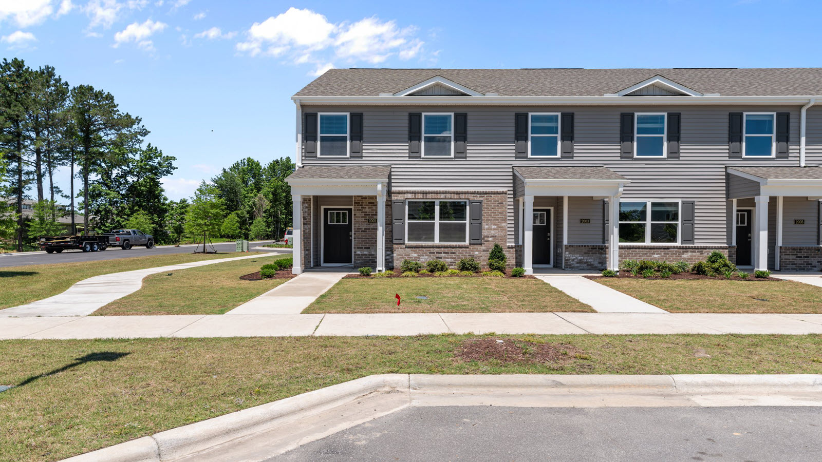 front exterior of the pearson floorplan townhome featuring light grey siding, stone accents and black shutters