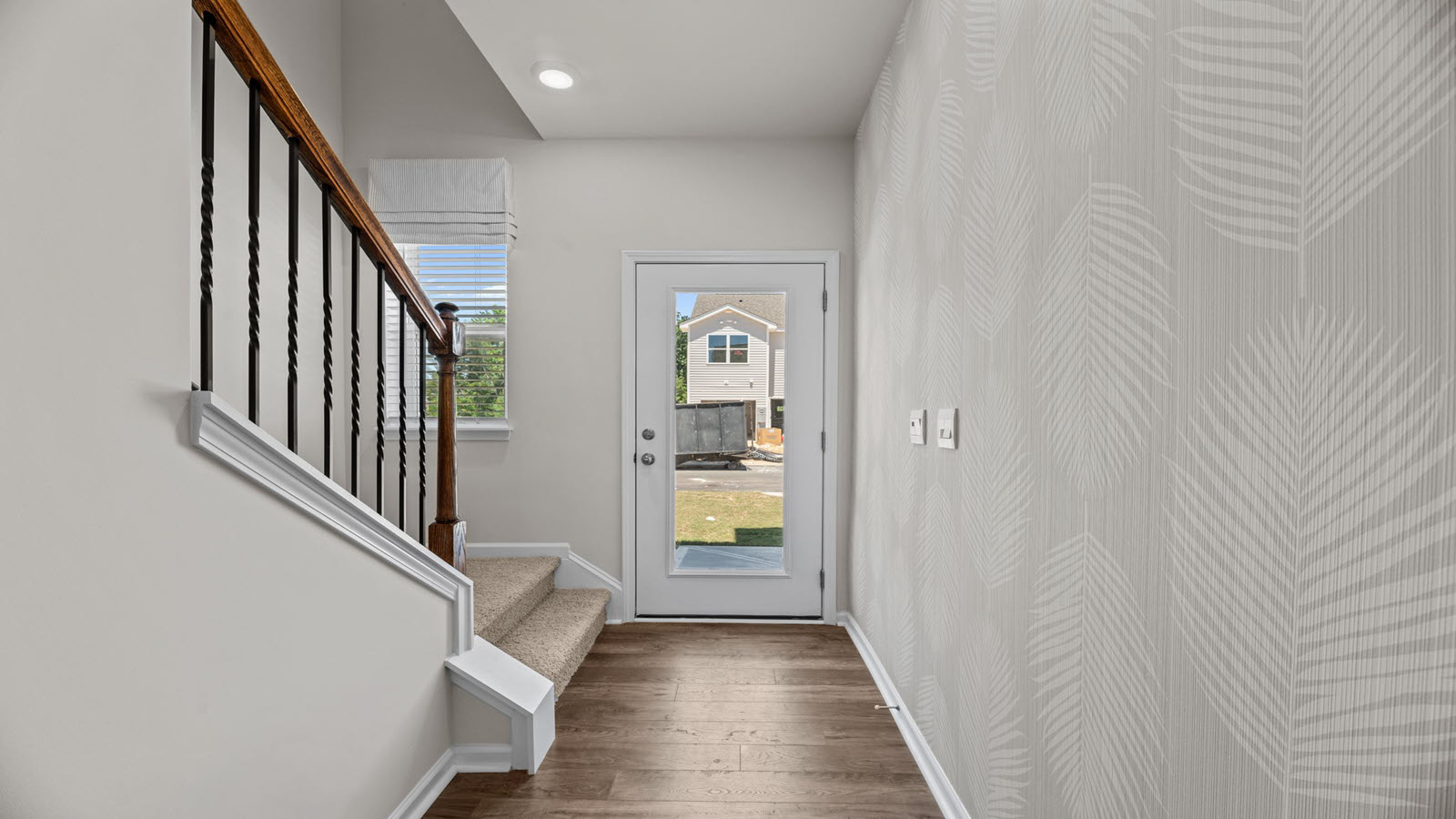hallway view of the front entry door with the staircase on the left