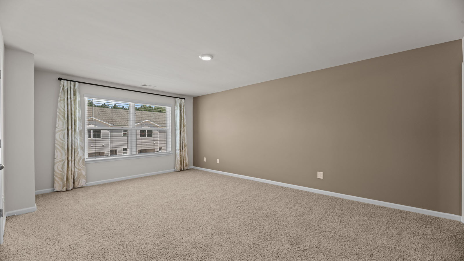 bedroom with light beige carpet and walls with a large window