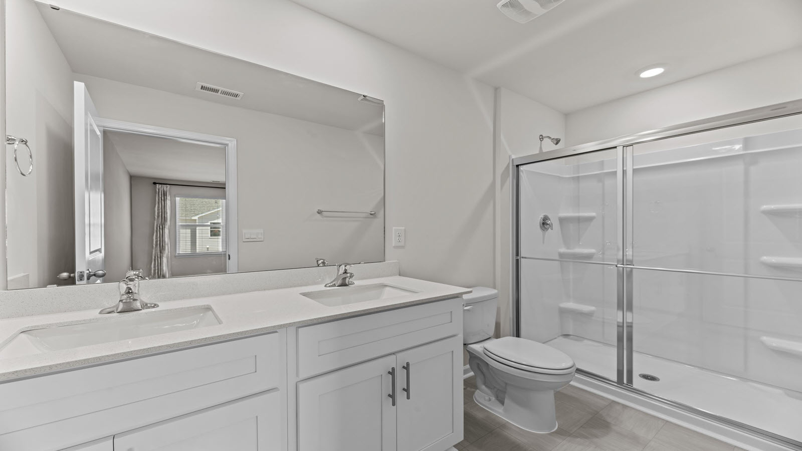 bathroom with dual vanity sinks, toilet and shower