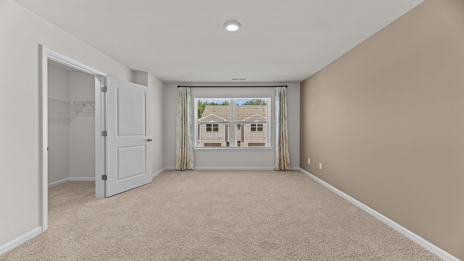 bedroom with light beige carpet and walls with a large window