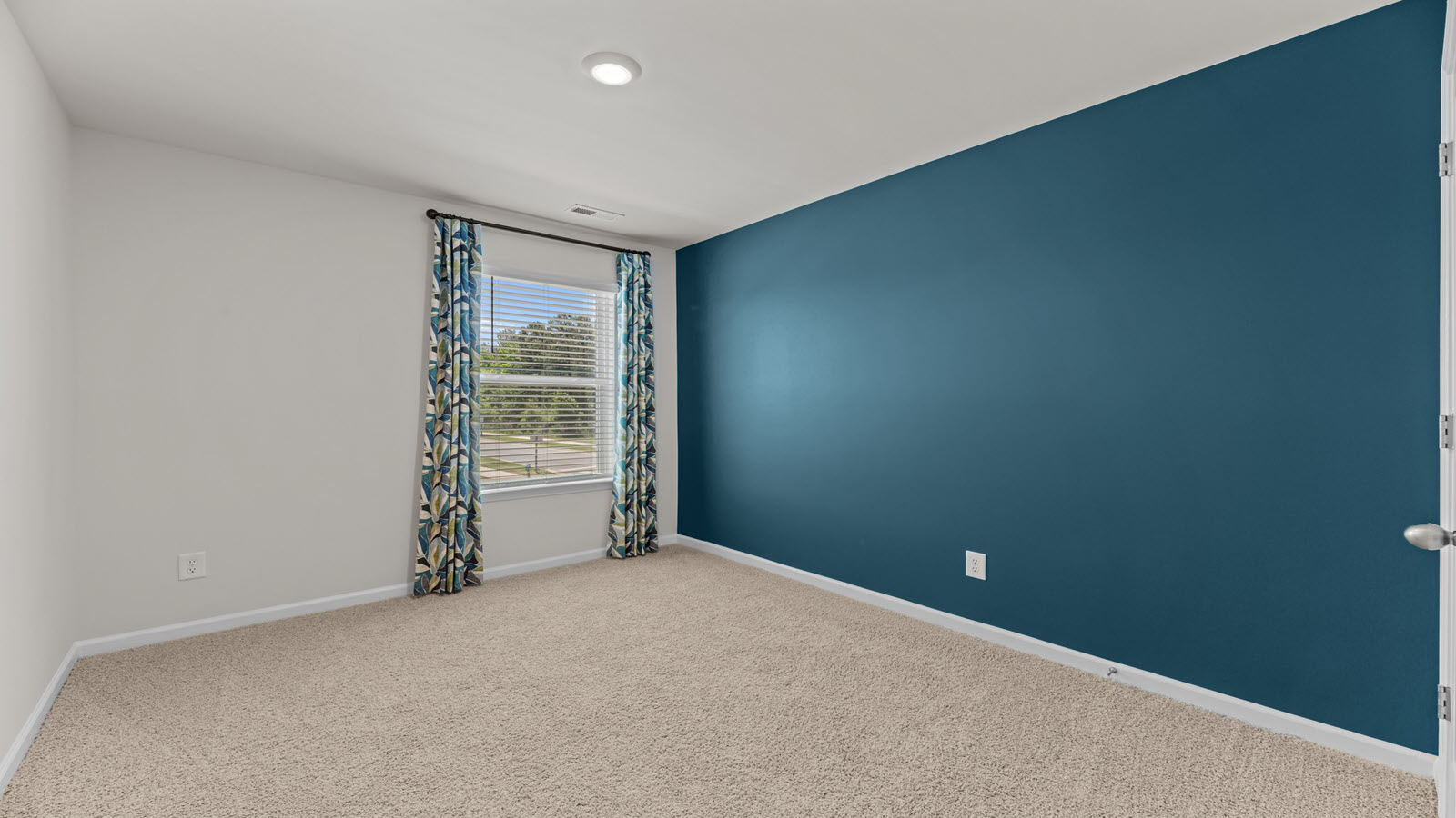 bedroom with a teal accent wall, beige carpet and a window