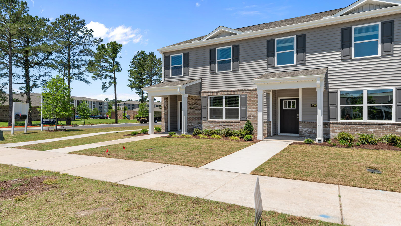 front exterior of the pearson floorplan townhome featuring light grey siding, stone accents and black shutters