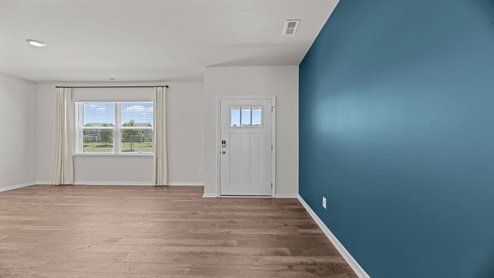 living room area with a teal accent wall just off the entry of home