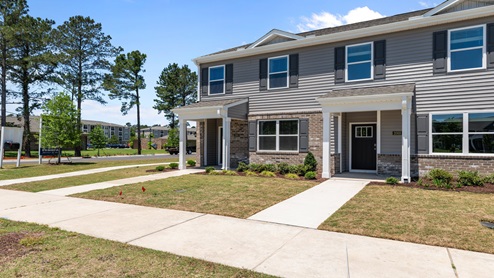 front exterior of the pearson floorplan townhome featuring light grey siding, stone accents and black shutters
