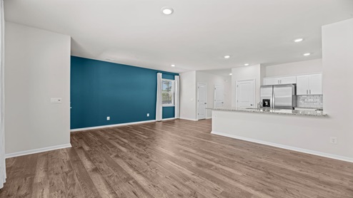 living room area with a teal accent wall just off the entry of home