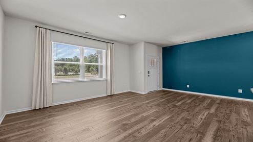 living room area with a teal accent wall just off the entry of home