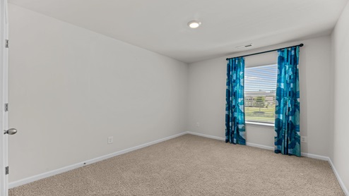 bedroom with beige carpet, white walls and a window with blue curtains