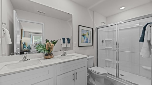 primary bathroom featuring a double-vanity sink, quartz counters, and shower-tub combo