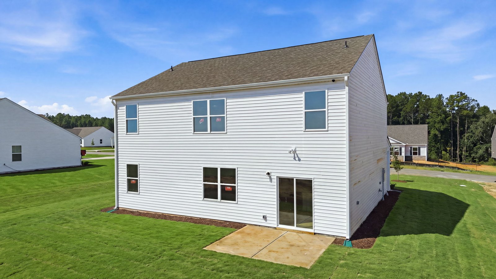 rear view of two story home with back yard and back patio pad