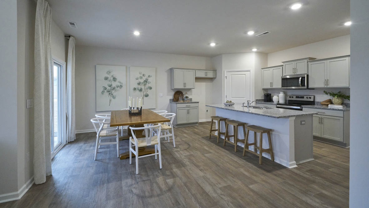 Spacious living room with brown flooring, white walls and windows