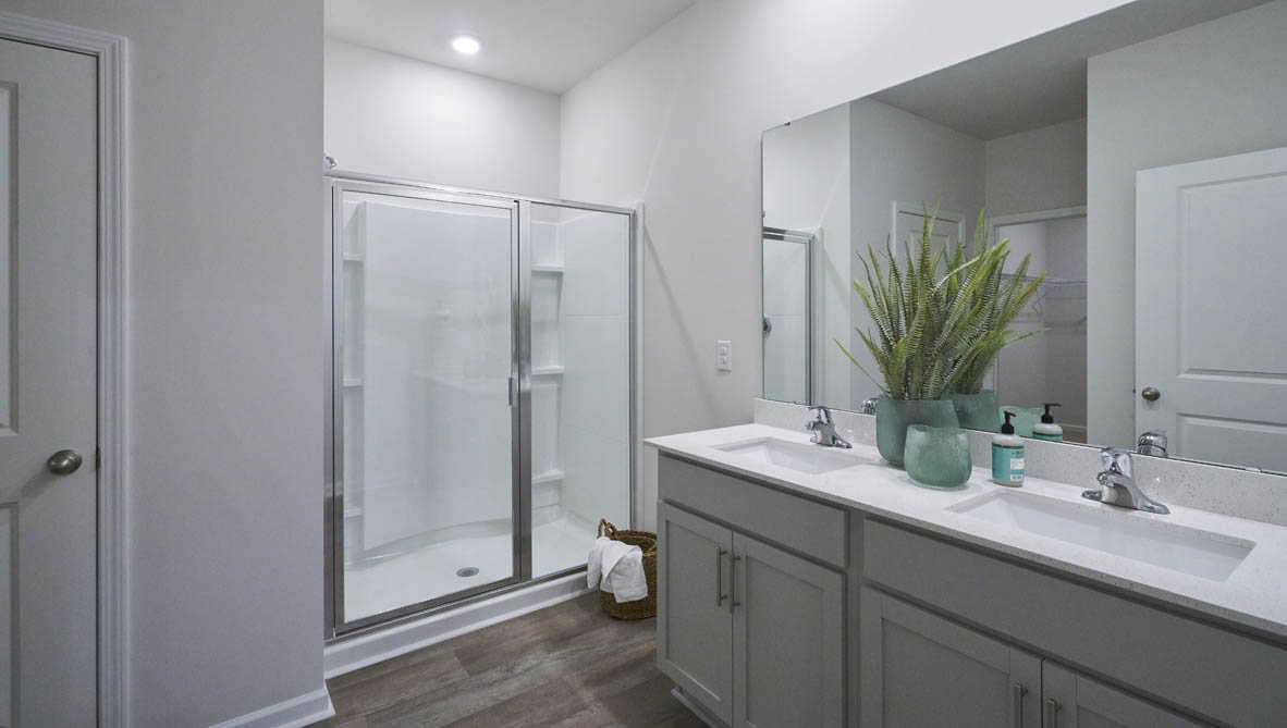 bathroom with dual vanity sinks, toilet, and a walk in shower