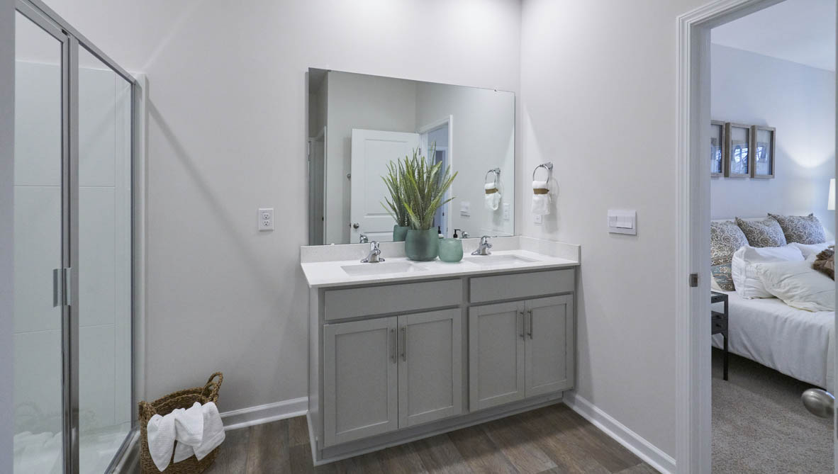 bathroom with dual vanity sinks, toilet, and a walk in shower
