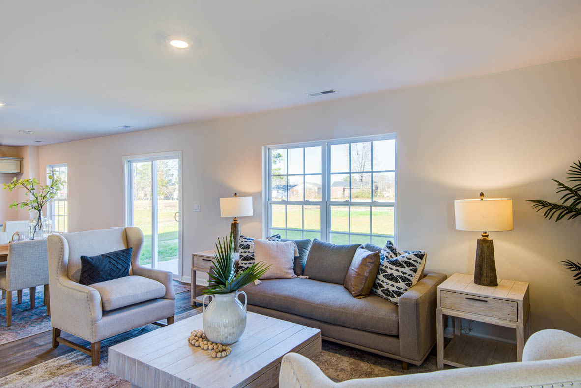 Spacious living room with brown flooring, white walls and windows