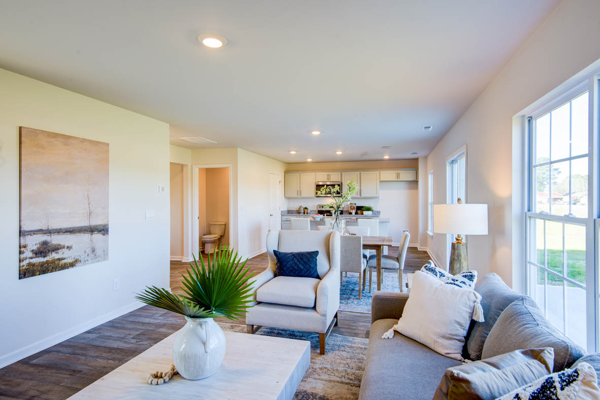 Spacious living room with brown flooring, white walls and windows