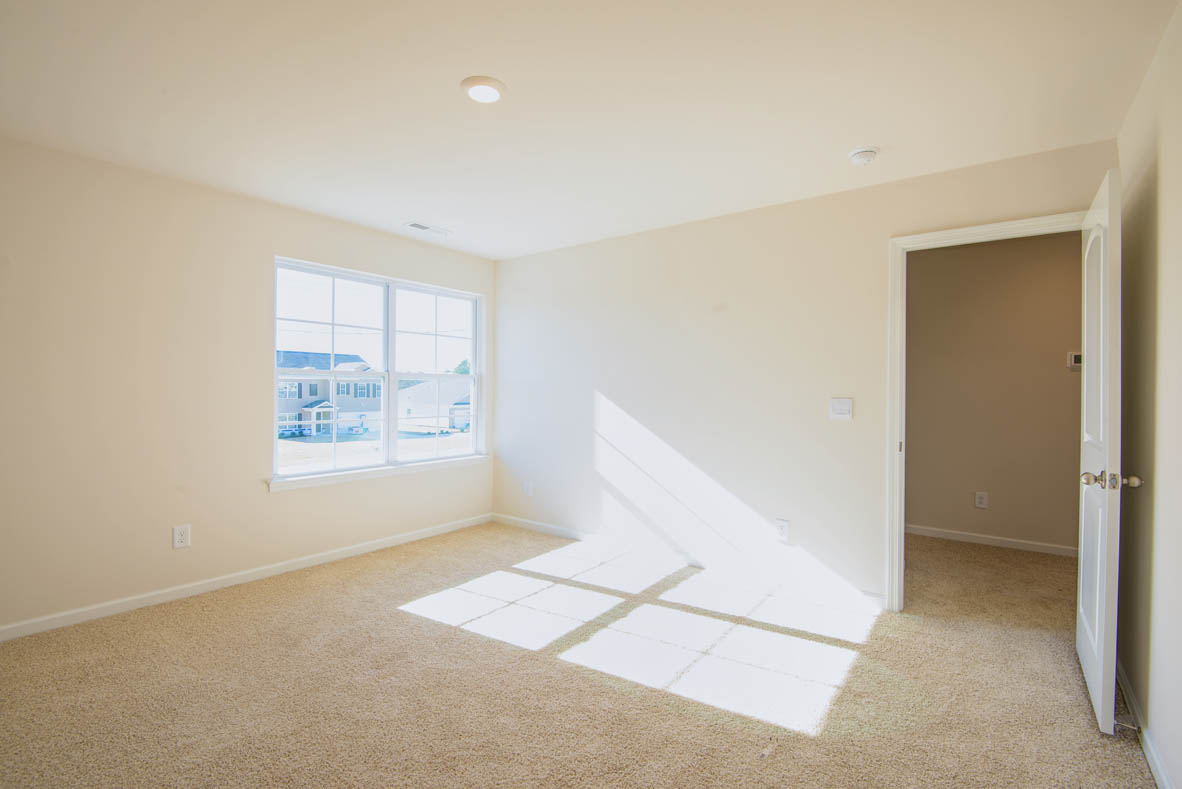 bedroom with beige carpet, beige walls and a window