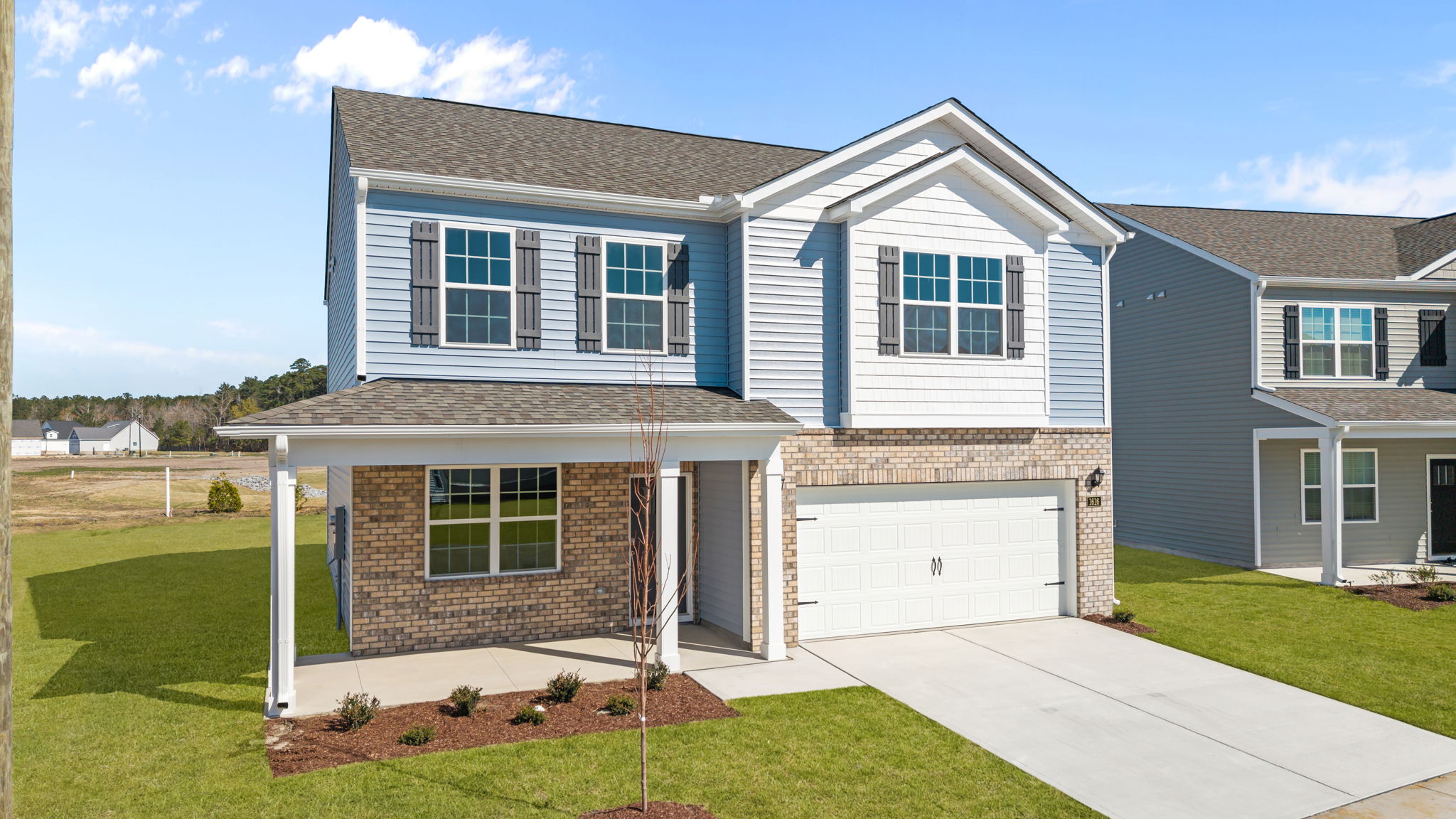 Two story blue and brick house with two car garage and covered front porch