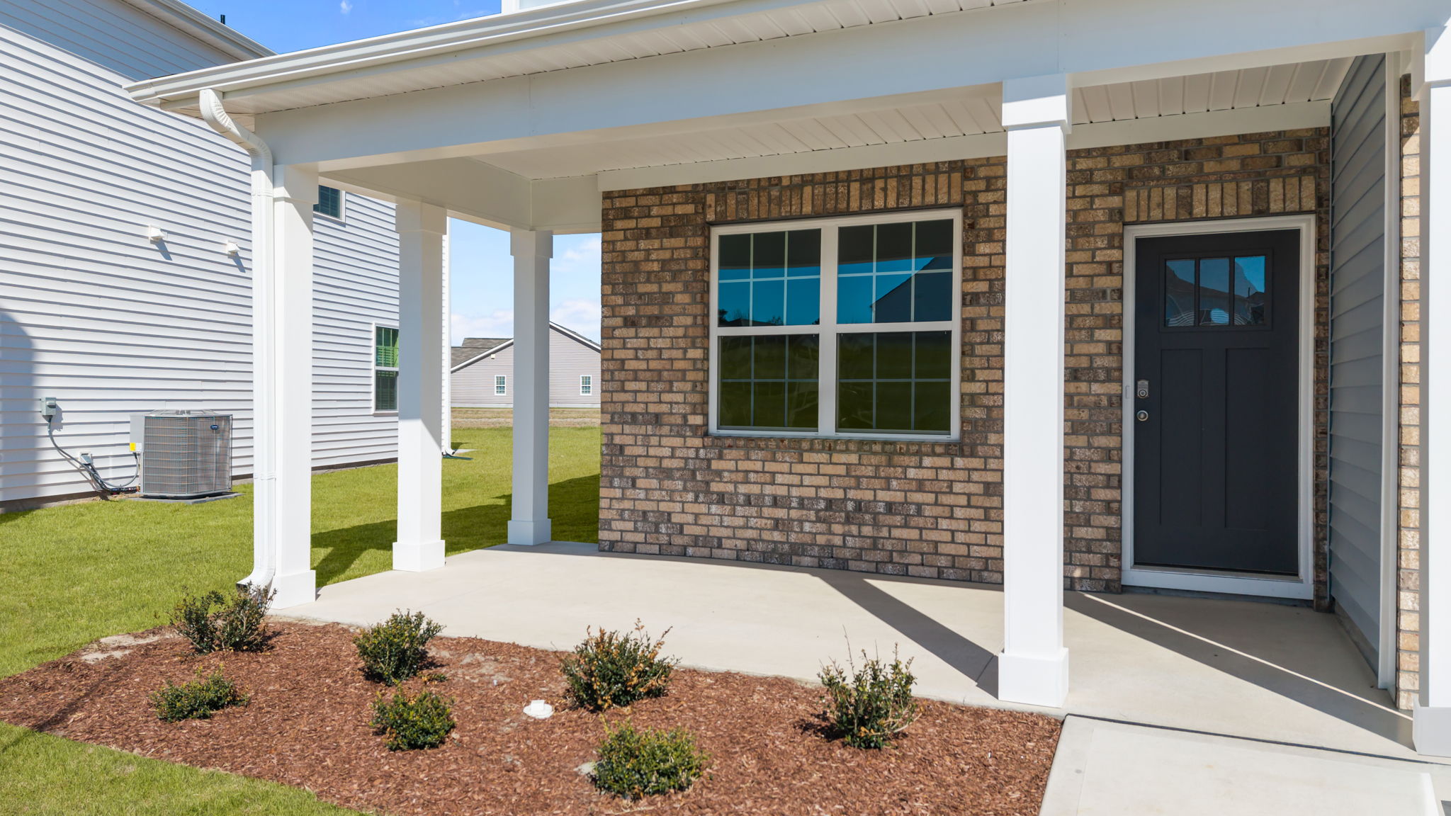 Covered front porch with beautiful beams and landscaping