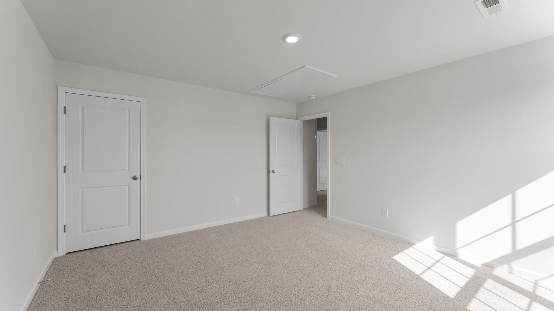bedroom with beige carpet, white walls and a window