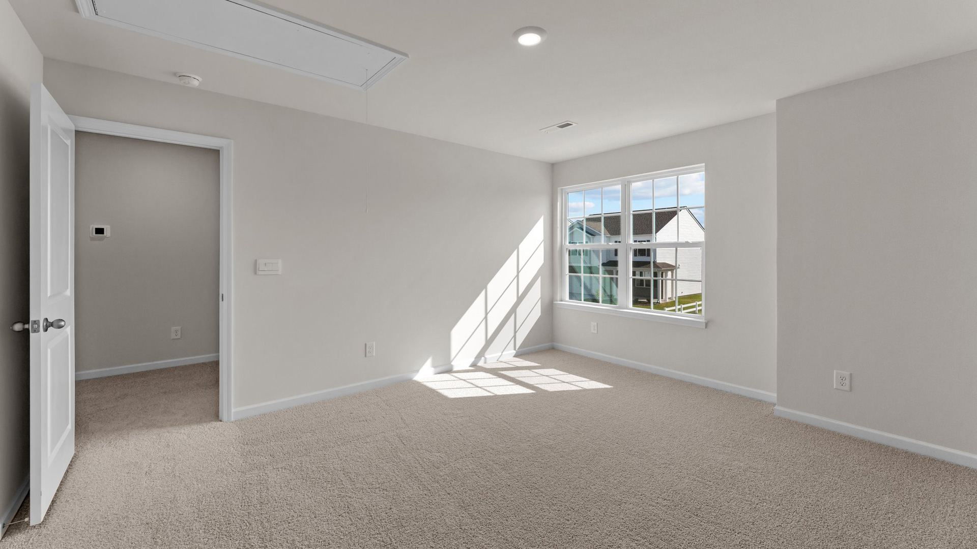 bedroom with beige carpet, white walls and a window