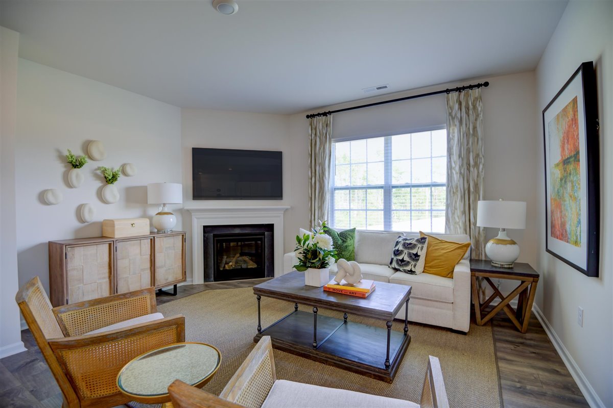 Spacious living room with brown flooring, white walls and windows