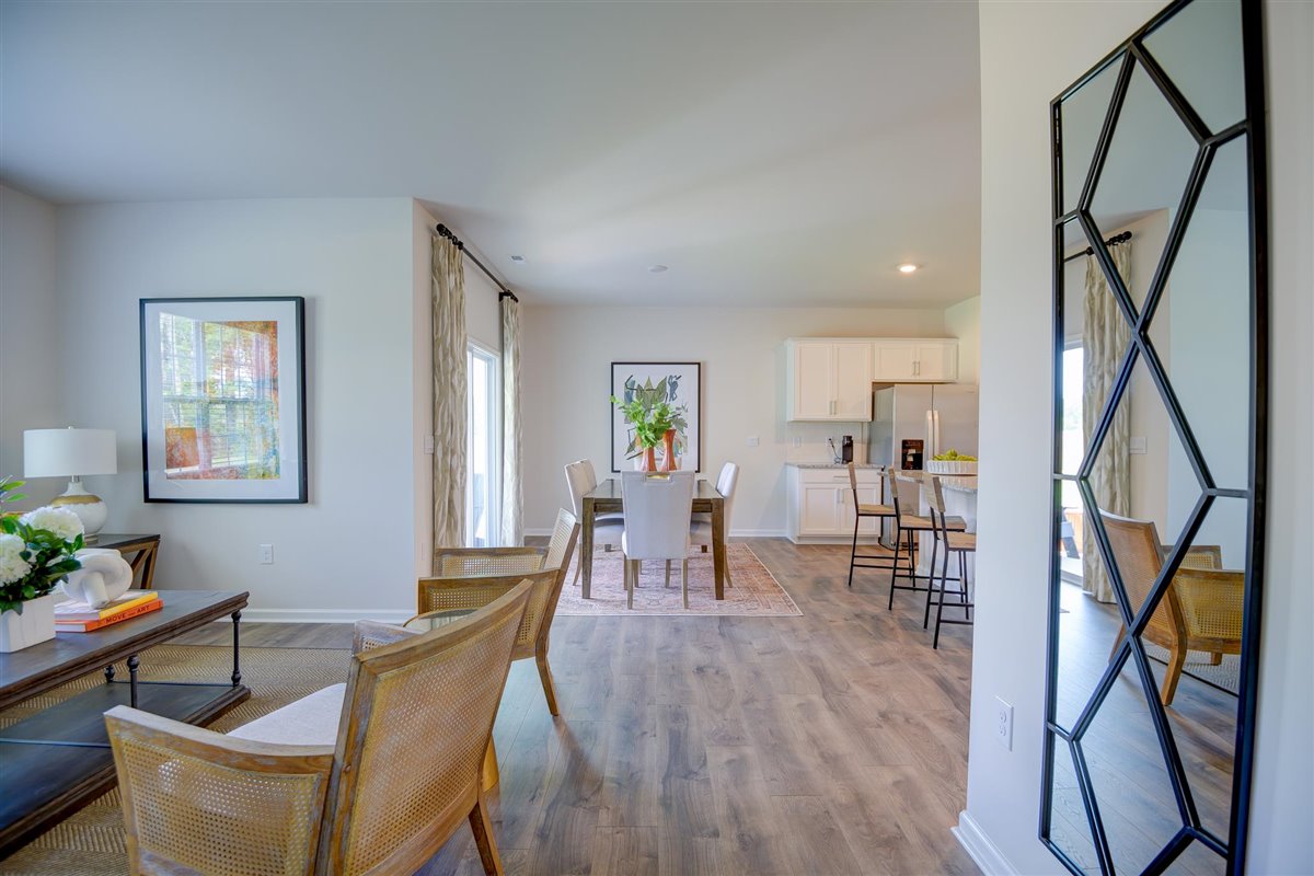 Spacious living room with brown flooring, white walls and windows