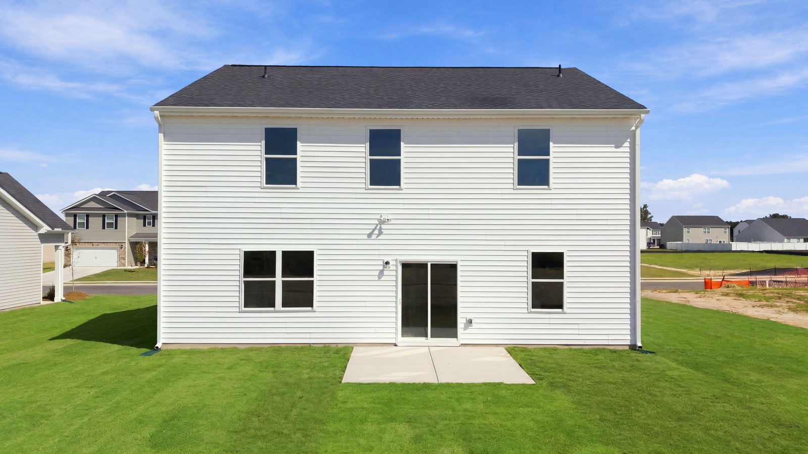 rear view of two story white home with back patio pad