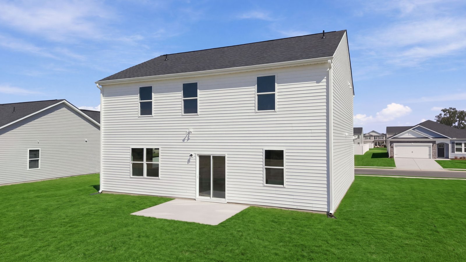 rear view of two story white home with back patio pad