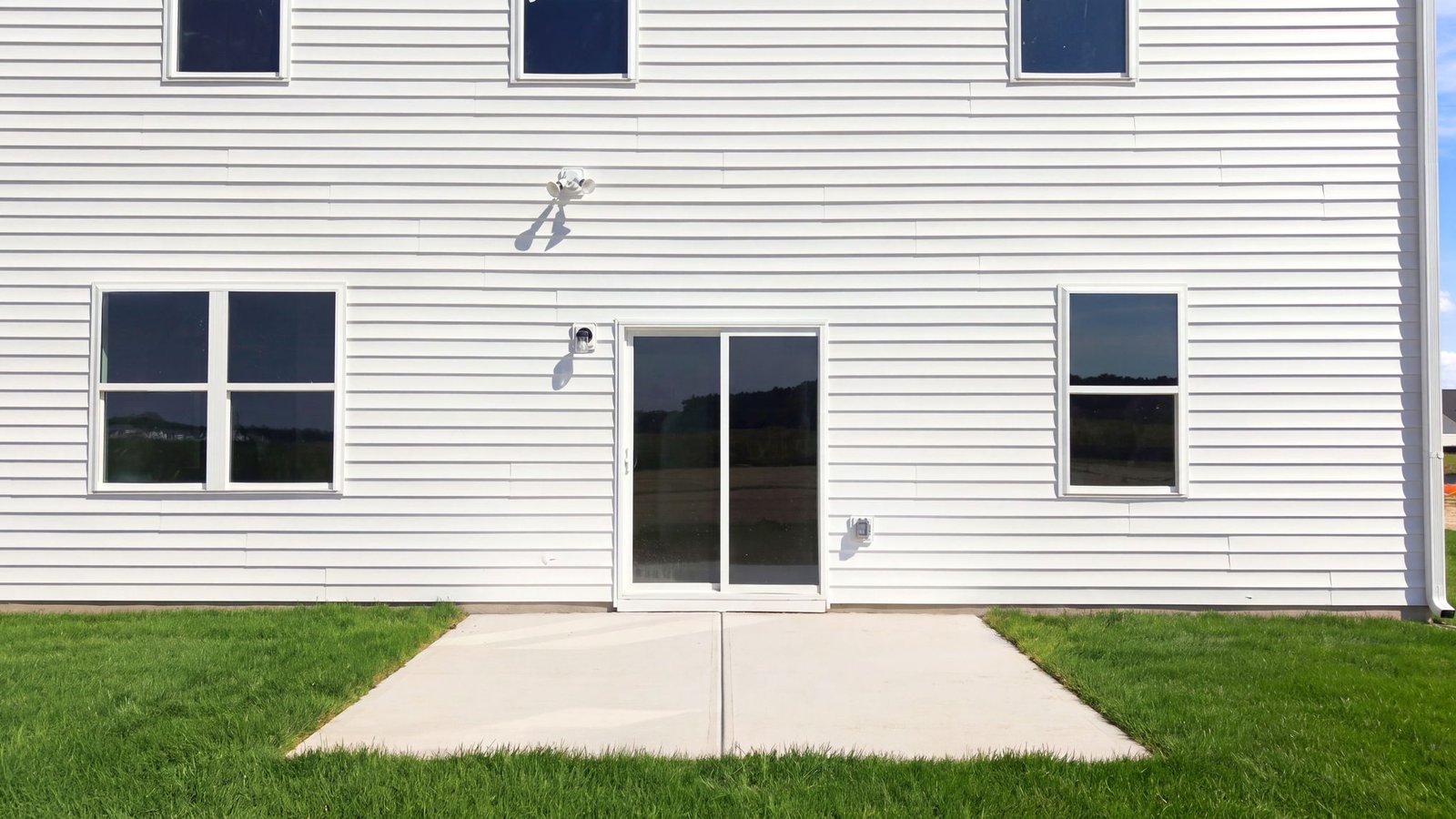 rear view of two story white home with back patio pad