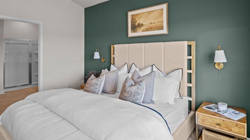 Primary bedroom with a green accent wall and carpet flooring with a large window