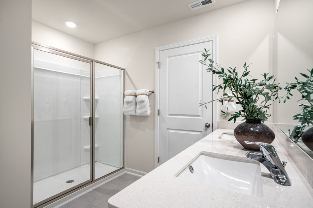 bathroom with dual vanity sinks, toilet, and a walk in shower