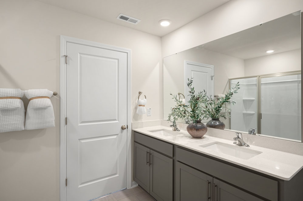 bathroom with dual vanity sinks, toilet, and a walk in shower