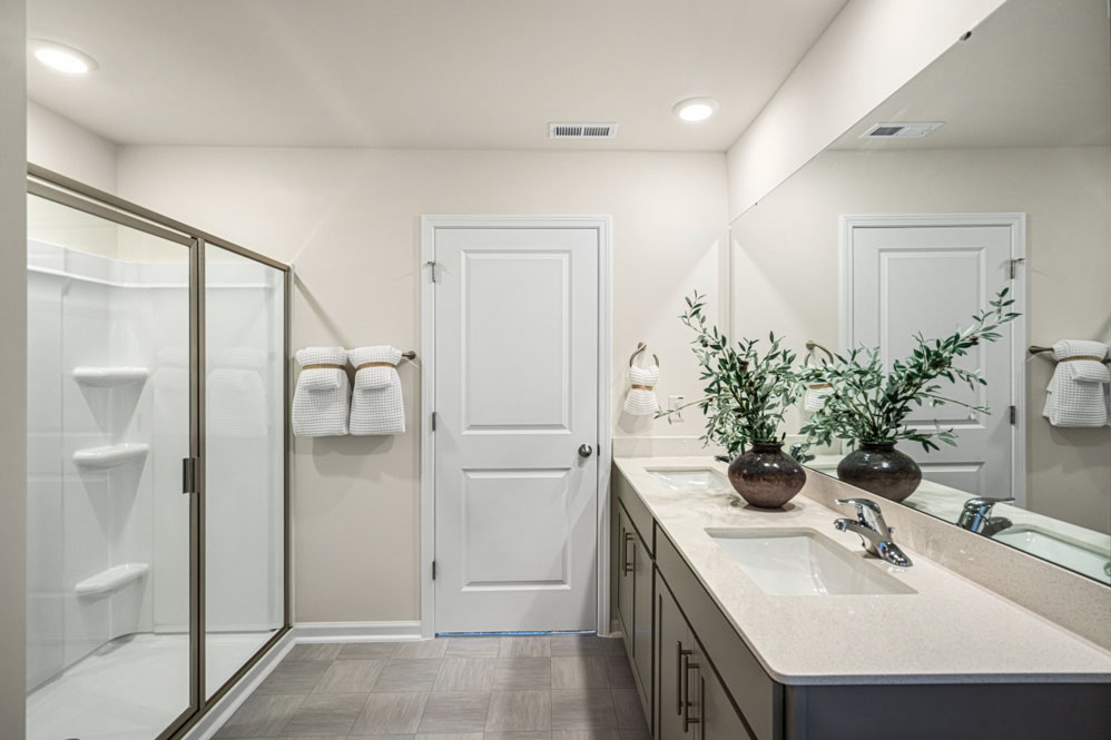bathroom with dual vanity sinks, toilet, and a walk in shower